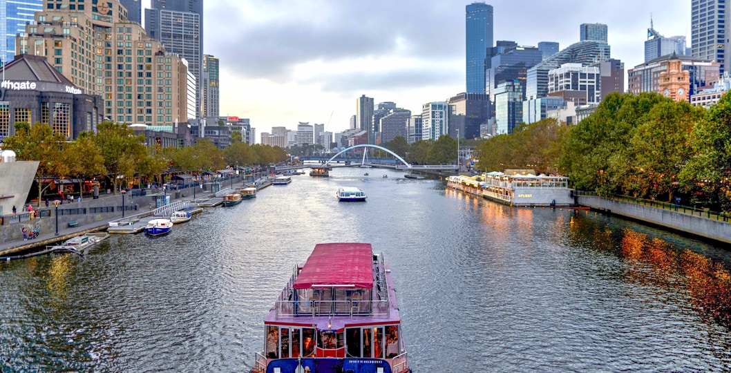 Melbourne River Cruises boat on Yarra River with city skyline in background.