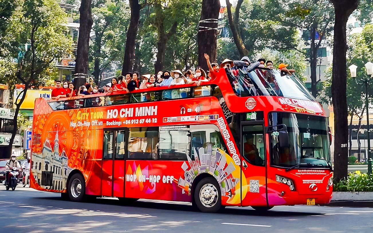 Double-decker bus on Ho Chi Minh City tour with passengers on top deck.