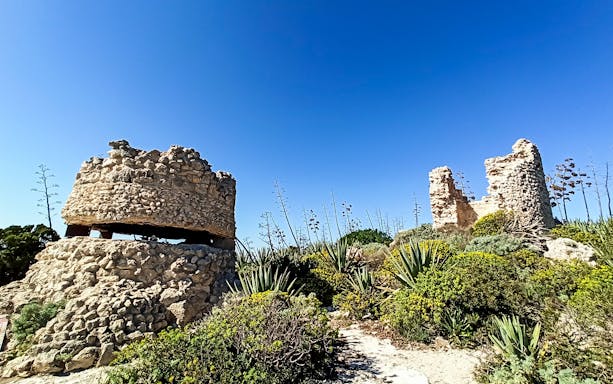 Ancient stone ruins surrounded by vegetation on the hike to the Devil’s Saddle in Sardinia.