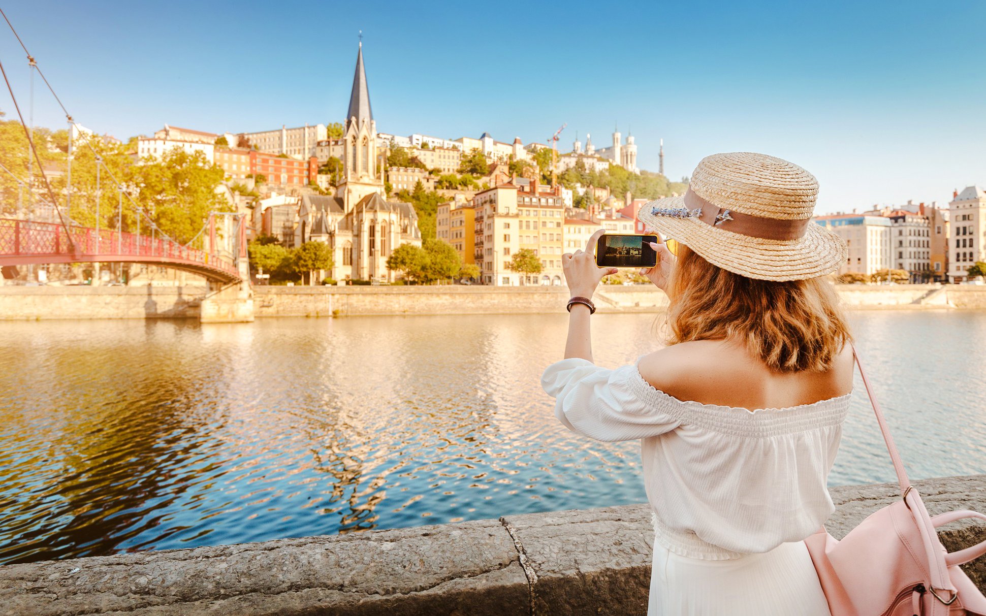 Woman photographing Lyon's Saône River and Saint George Church, France.