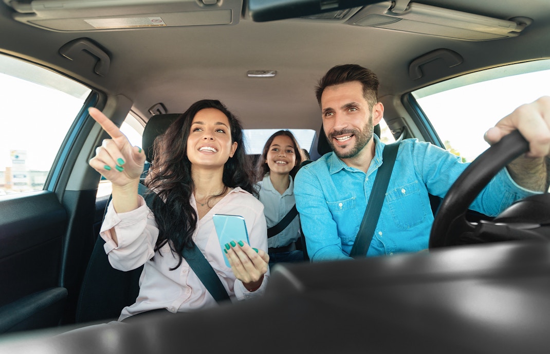 Family driving through scenic countryside towards a travel destination.