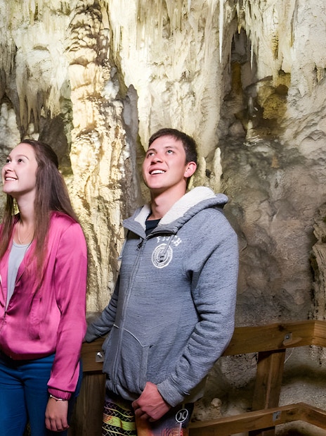 Visitors exploring Waitomo Glowworm Caves in Auckland, viewing stalactites and stalagmites.