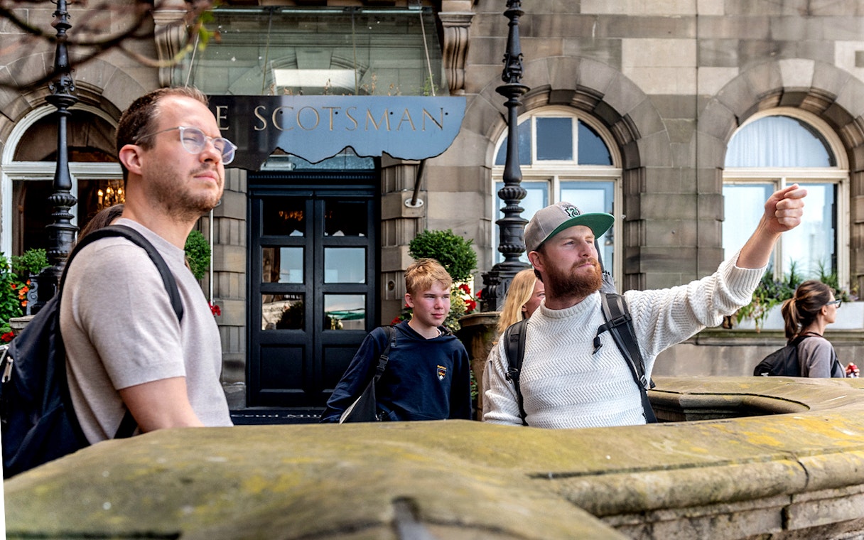 Tour guide leading Harry Potter walking tour in front of The Scotsman Hotel, Edinburgh.