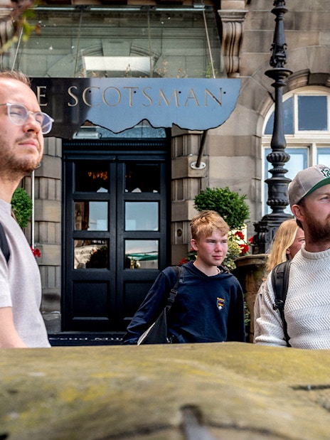 Tour guide leading Harry Potter walking tour in front of The Scotsman Hotel, Edinburgh.