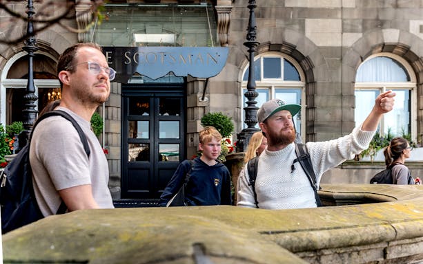Tour guide leading Harry Potter walking tour in front of The Scotsman Hotel, Edinburgh.
