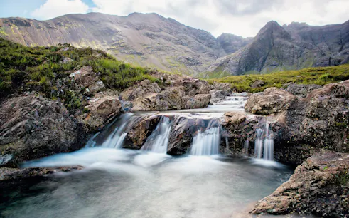 Waterfalls cascading over rocks at the Fairy Pools, Isle of Skye, Scotland.