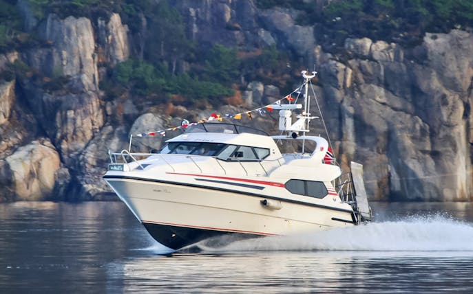 Cruise boat on Lysefjord with rocky cliffs in the background, Norway.