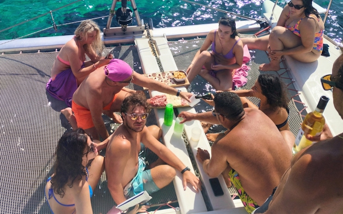 Group enjoying a meal on a catamaran tour in La Maddalena.