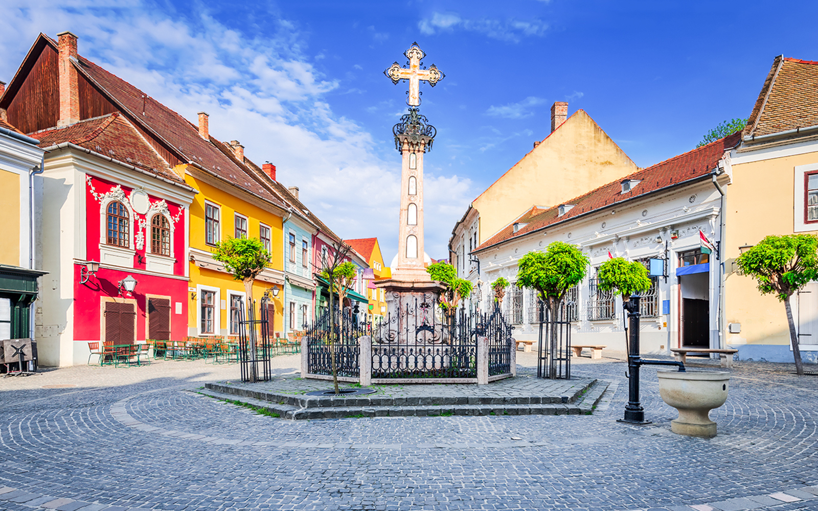 Szentendre village center with colorful buildings and a central cross monument.