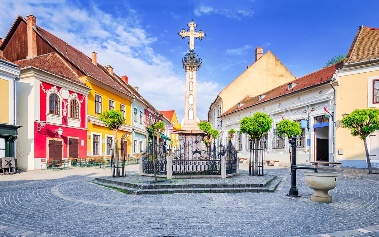 Szentendre village center with colorful buildings and a central cross monument.