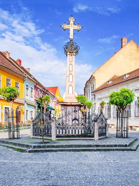 Szentendre village center with colorful buildings and a central cross monument.