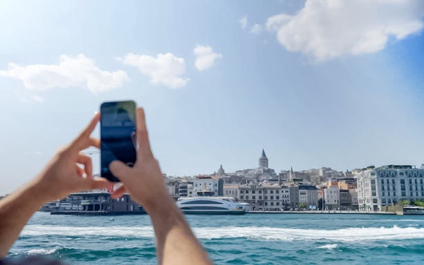 Tourist photographing Galata Tower during Bosphorus Golden Horn Cruise in Istanbul.