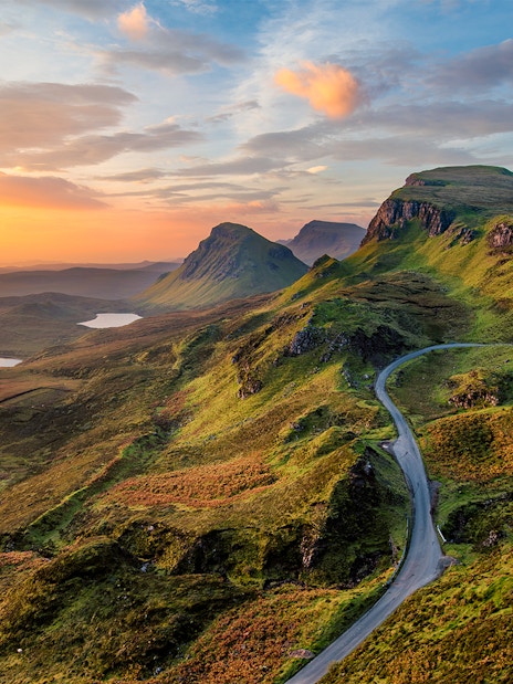 Sunrise over rolling hills and lochs in the Scottish Highlands.