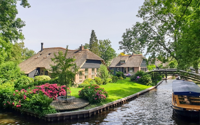 Thatched cottages and canal in Giethoorn, Netherlands, seen on a day trip from Amsterdam by bus and boat.