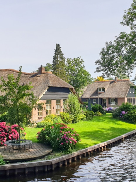 Thatched cottages and canal in Giethoorn, Netherlands, seen on a day trip from Amsterdam by bus and boat.