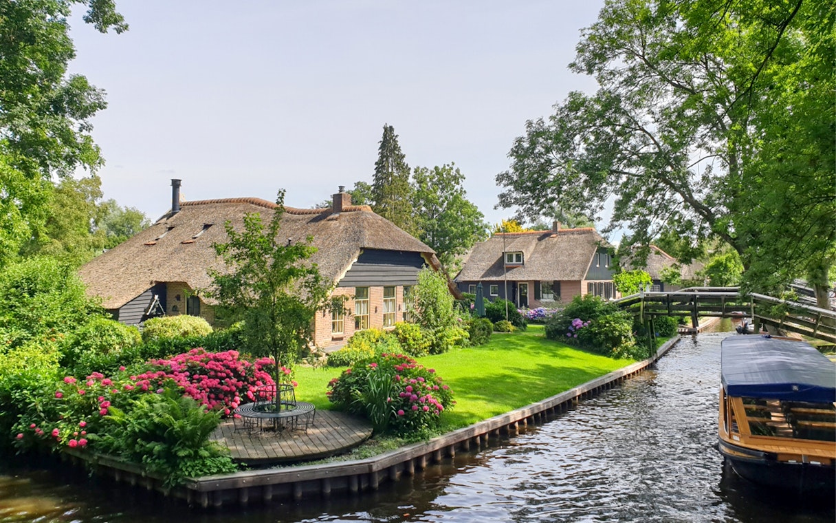 Thatched cottages and canal in Giethoorn, Netherlands, seen on a day trip from Amsterdam by bus and boat.