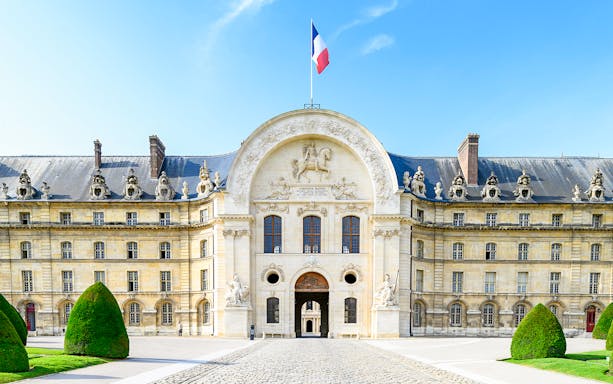Front entrance of The Army Museum in Paris with French flag above.