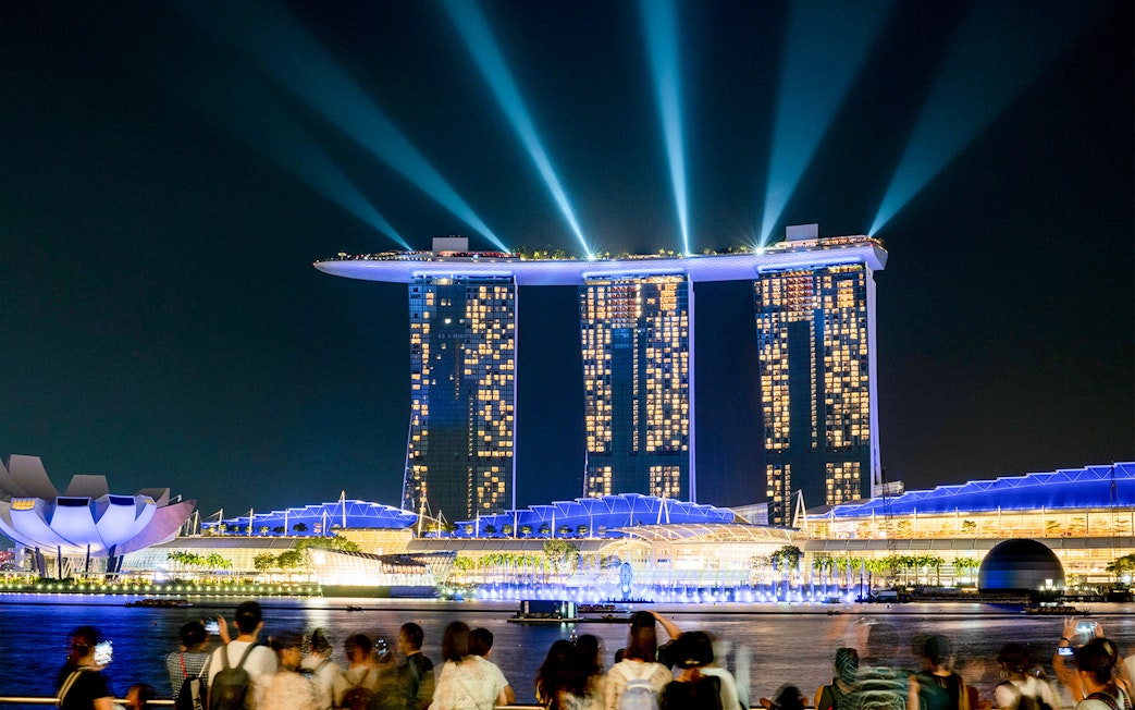 Marina Bay Sands SkyPark illuminated at night in Singapore with crowds viewing.