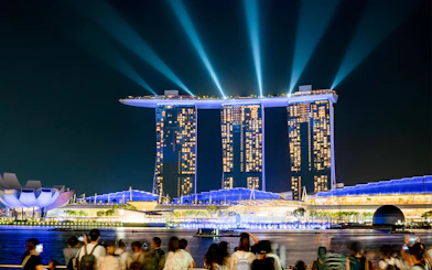 Marina Bay Sands SkyPark illuminated at night in Singapore with crowds viewing.