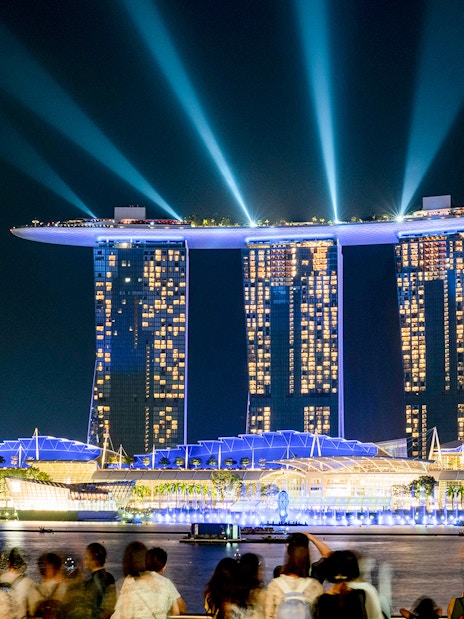 Marina Bay Sands SkyPark illuminated at night in Singapore with crowds viewing.