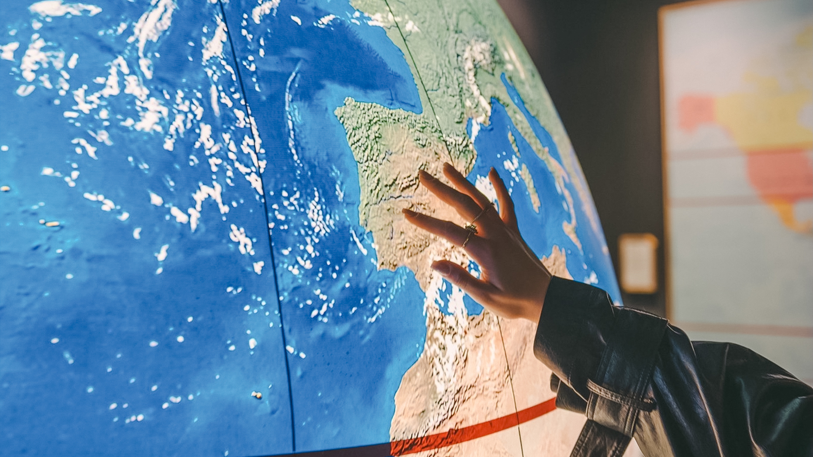 Hand touching a map of Europe, highlighting Spain for The Wine Experience tour.