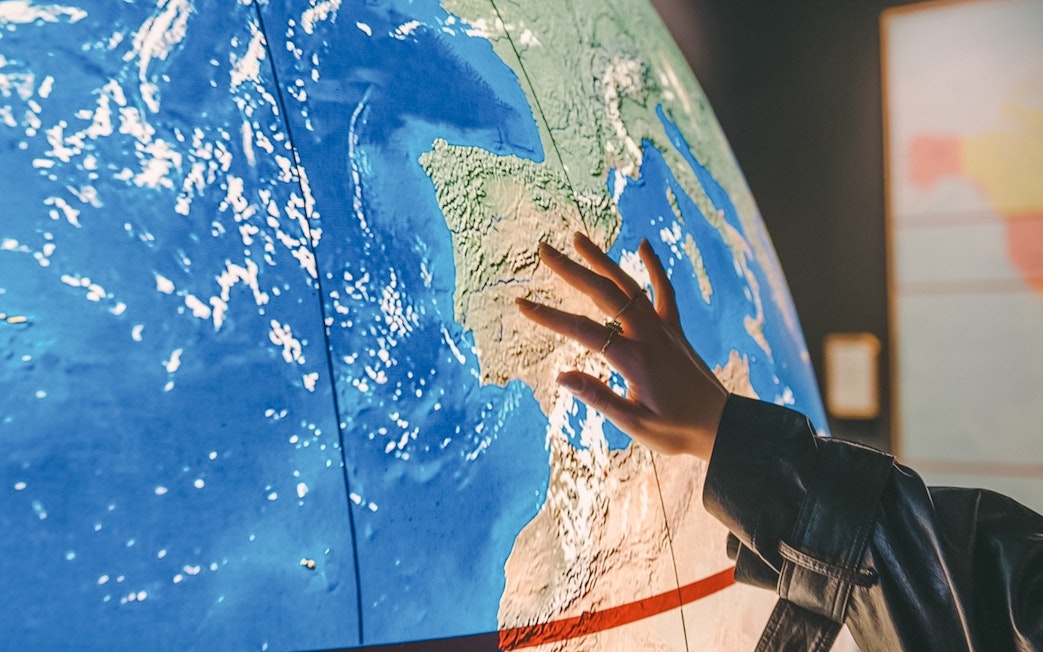 Hand touching a map of Europe, highlighting Spain for The Wine Experience tour.