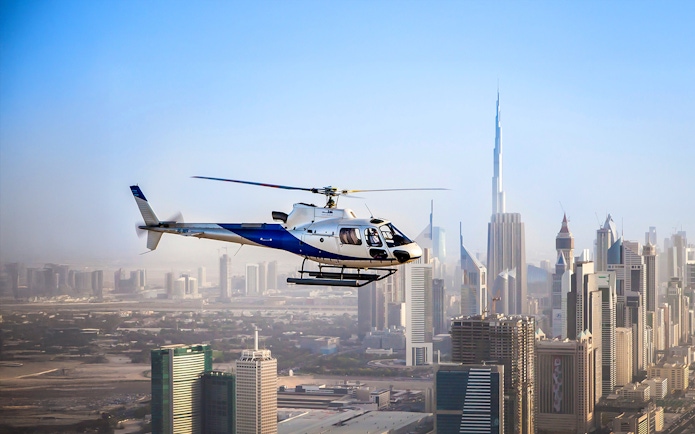 Helicopter flying over Dubai skyline with Burj Khalifa in view.