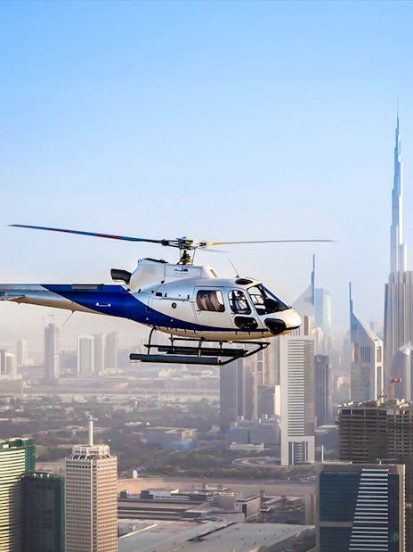 Helicopter flying over Dubai skyline with Burj Khalifa in view.