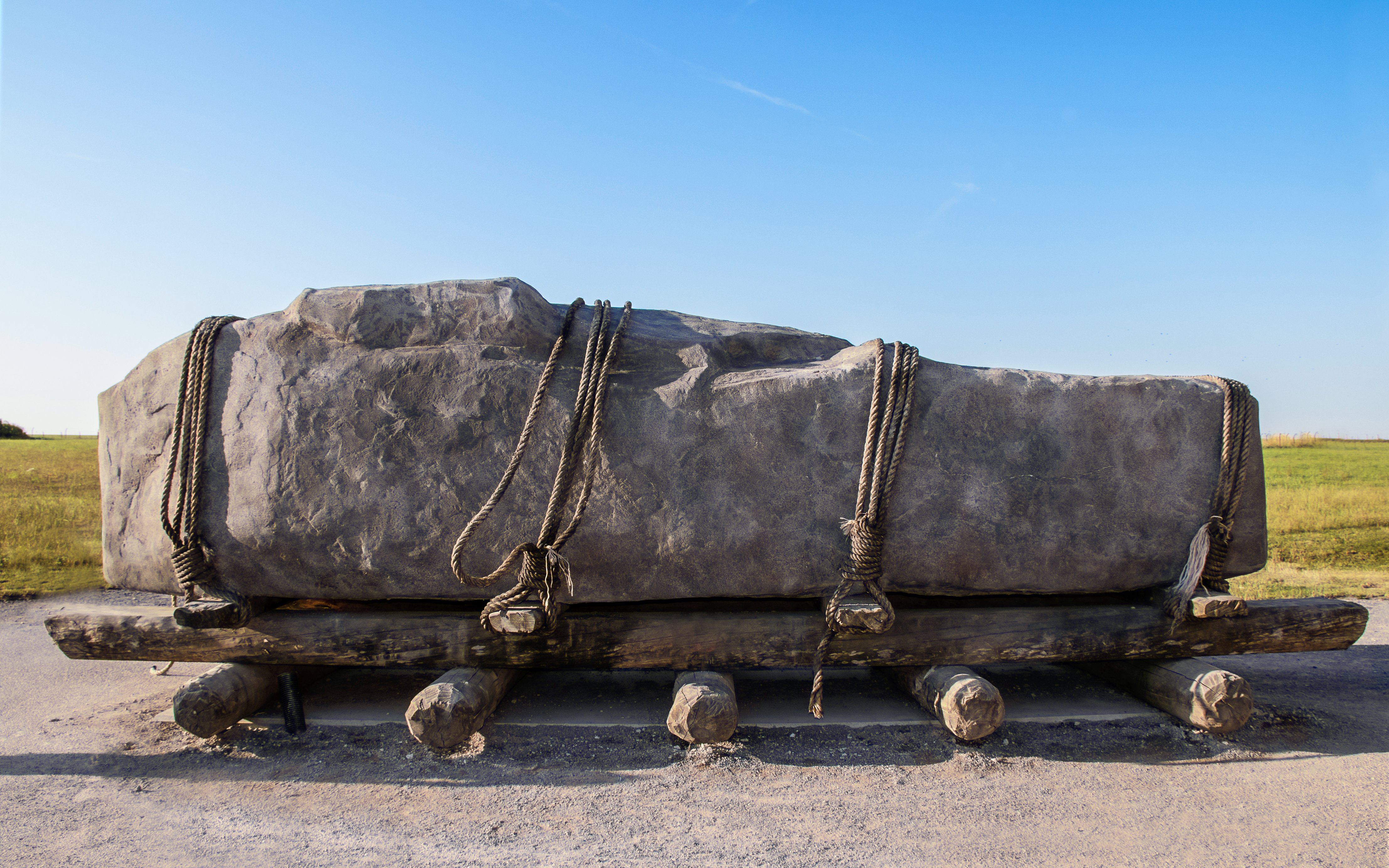 Stone on wooden sledge with rollers and ropes, illustrating ancient transport methods.