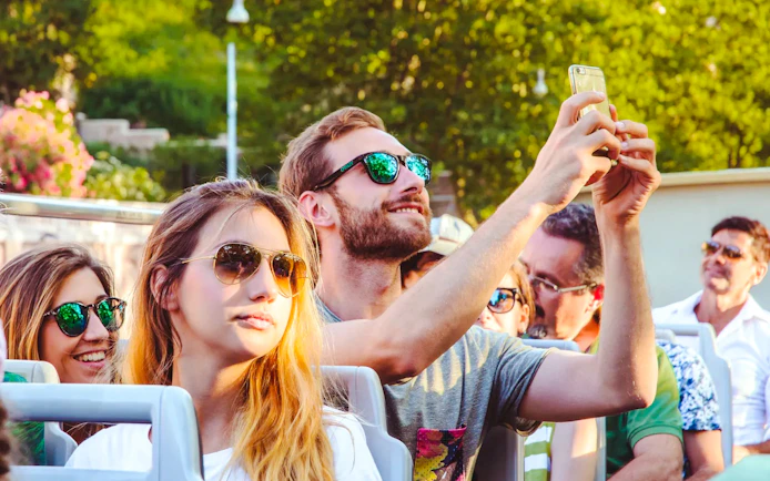 Person taking a photo on a phone during a hop-on hop-off bus tour.