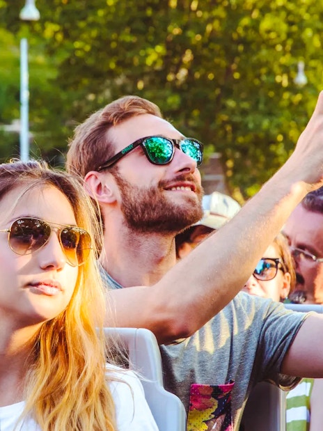 Person taking a photo on a phone during a hop-on hop-off bus tour.