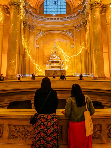 Visitors observing Aura Immersive light display at Invalides, Paris.