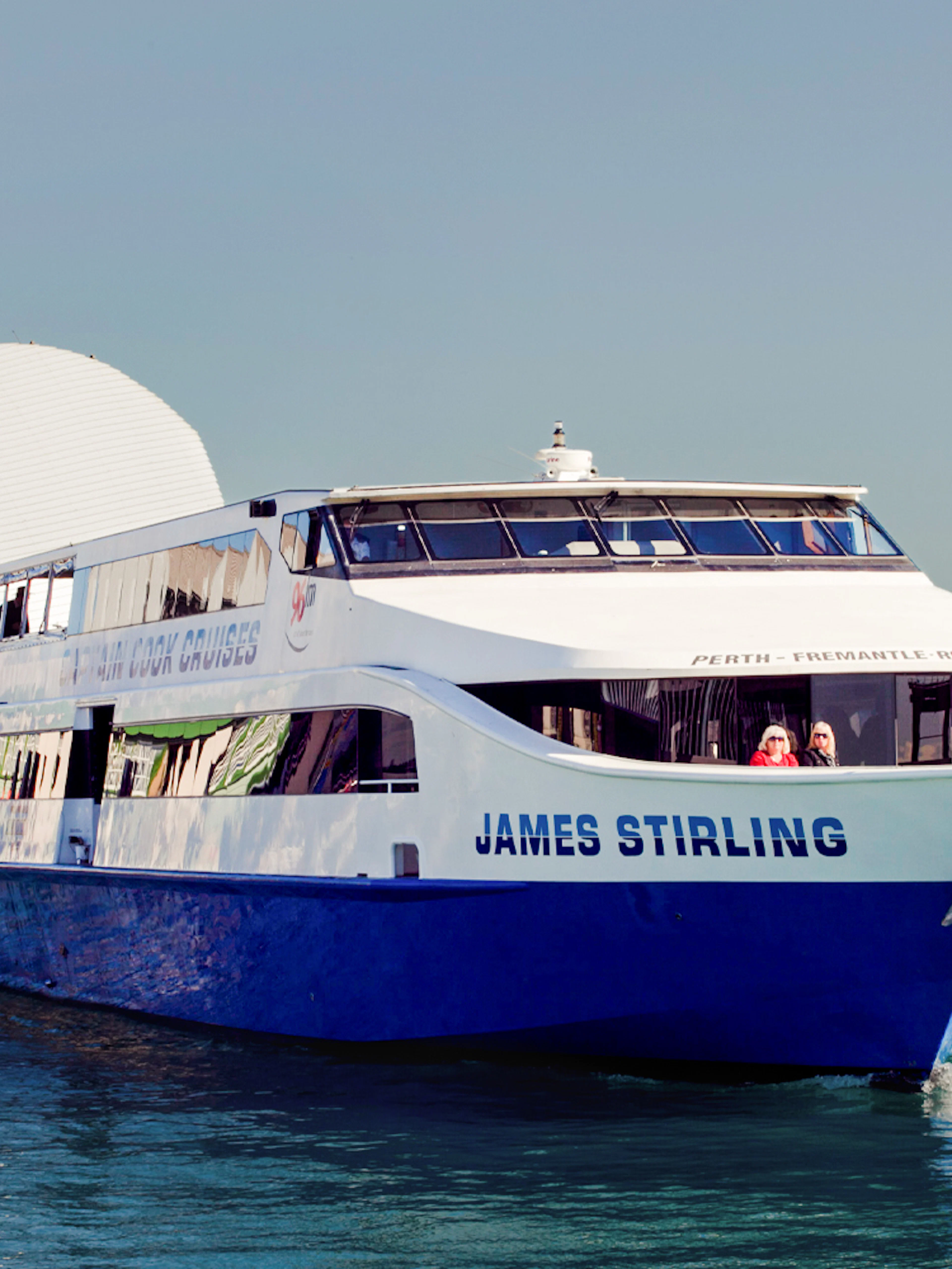 Cruise boat on Perth's Swan River near waterfront buildings.