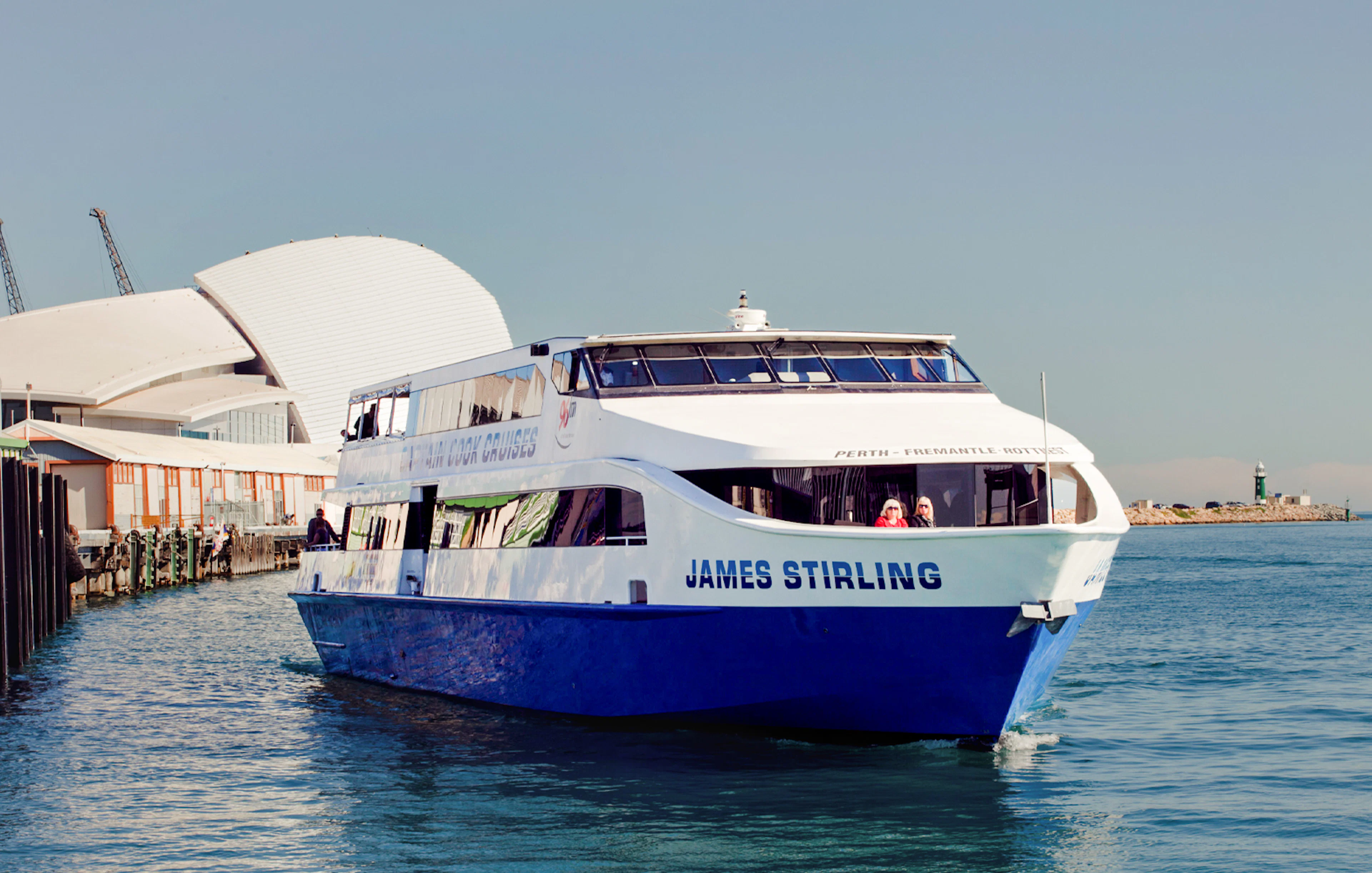 Cruise boat on Perth's Swan River near waterfront buildings.