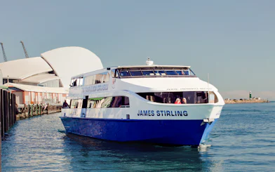 Cruise boat on Perth's Swan River near waterfront buildings.