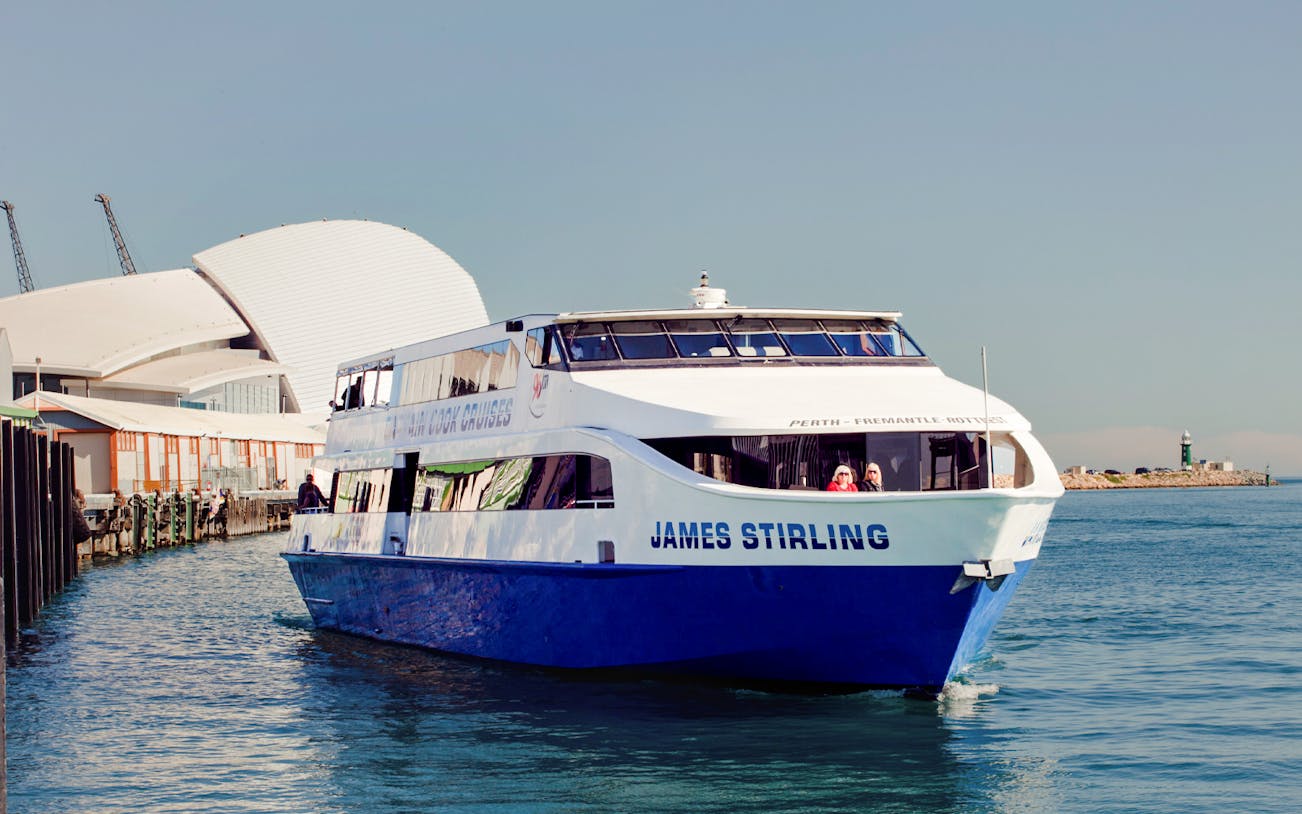 Cruise boat on Perth's Swan River near waterfront buildings.