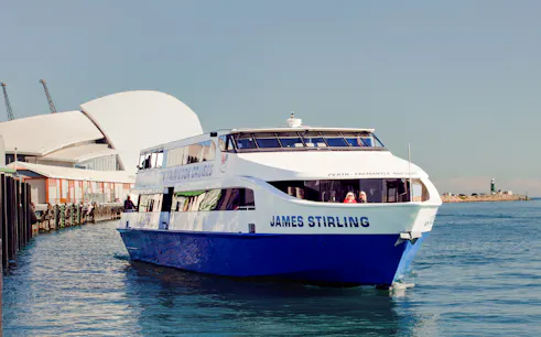 Cruise boat on Perth's Swan River near waterfront buildings.
