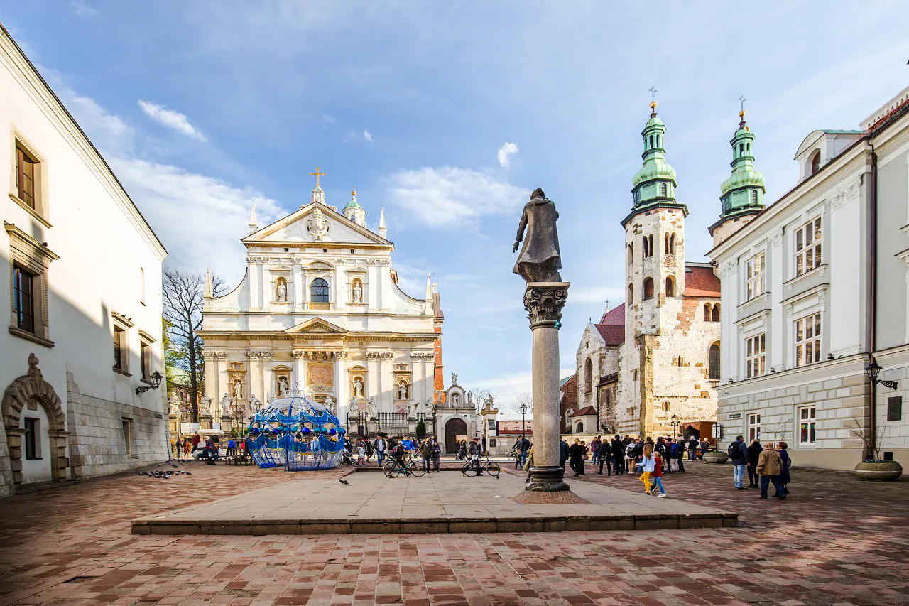 Krakow Old Town square with historic church and tourists exploring.