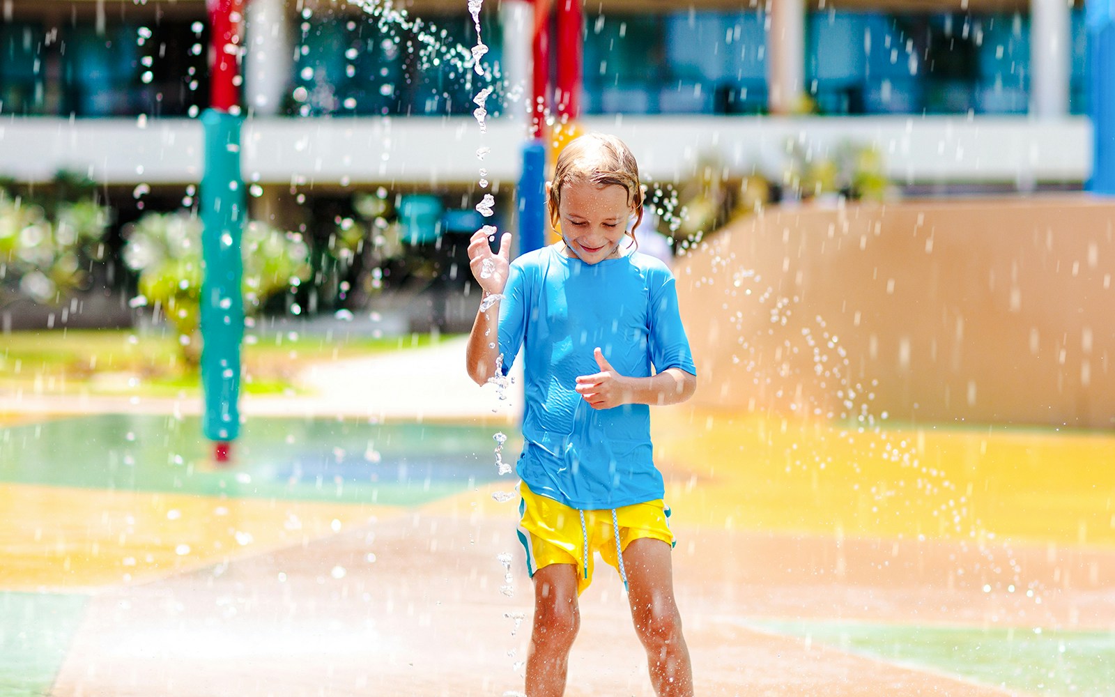 Child playing in water park splash zone.
