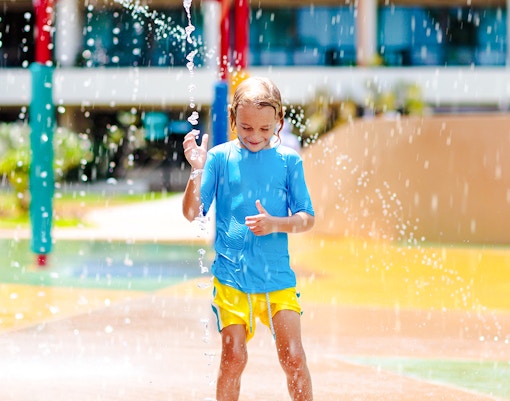 Child playing in water park splash zone.