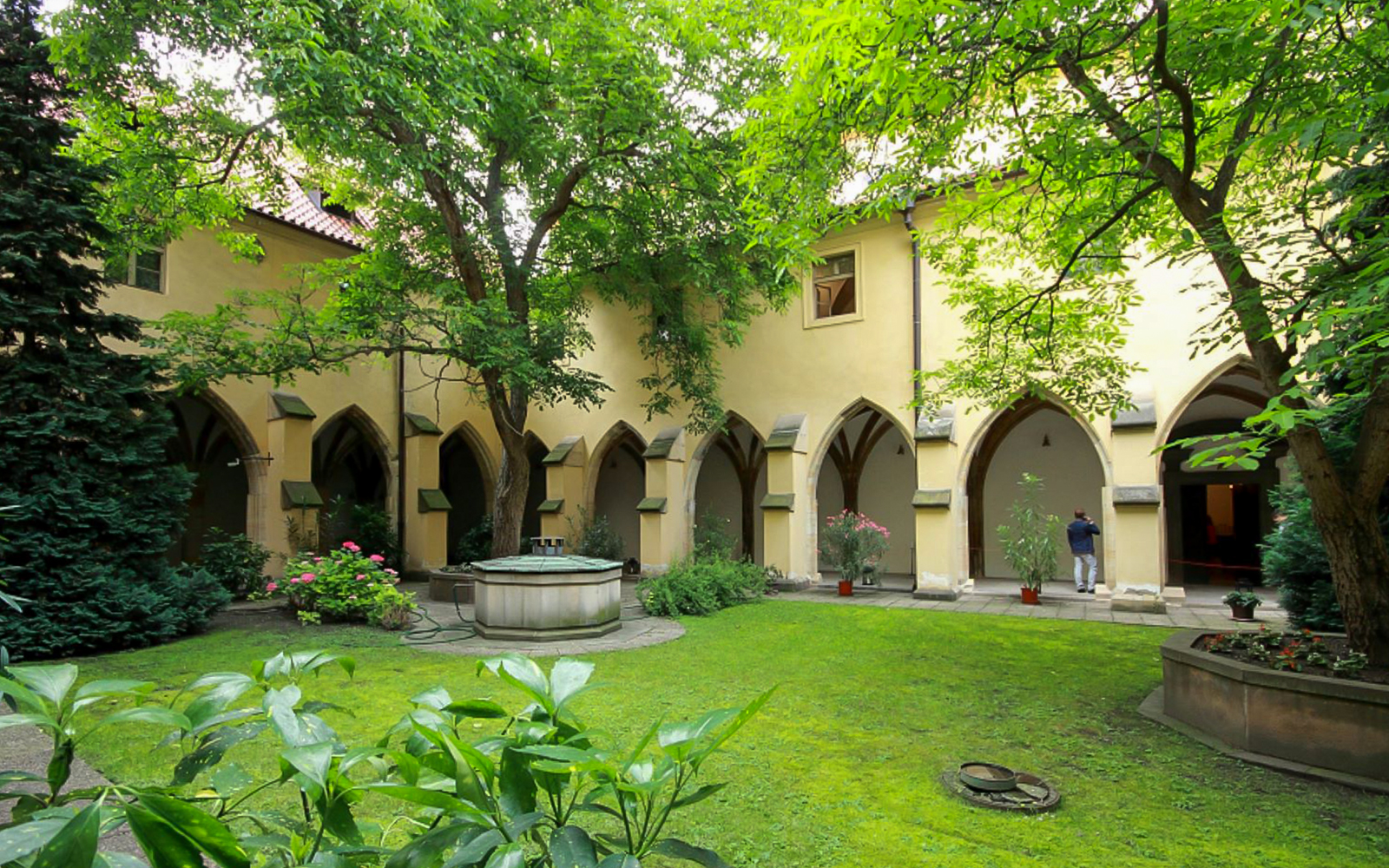 Courtyard of Minorite Monastery of St James in Prague with arches and greenery.