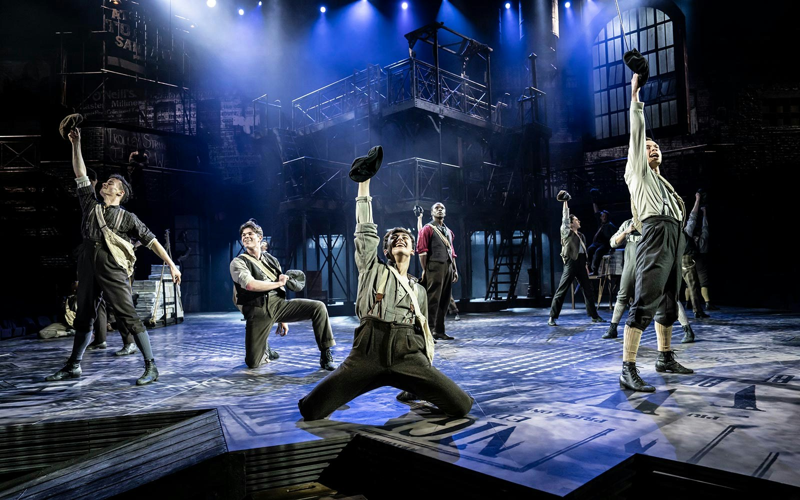 Performers on stage during a dynamic scene from the musical "Newsies.
