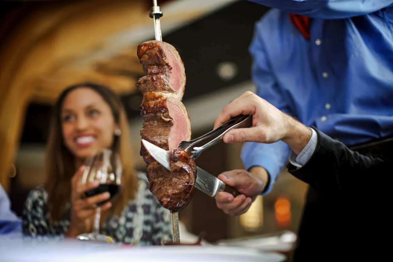 Server slicing meat at Brazilian steakhouse in Rio de Janeiro.