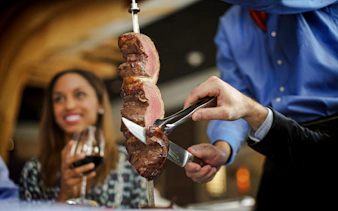 Server slicing meat at Brazilian steakhouse in Rio de Janeiro.