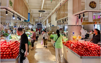 Local market in Chongqing with people shopping for fresh produce.