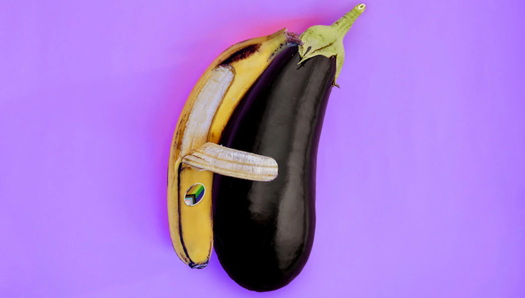 A banana and eggplant arranged to resemble an animal on a purple background.