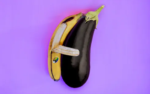 A banana and eggplant arranged to resemble an animal on a purple background.
