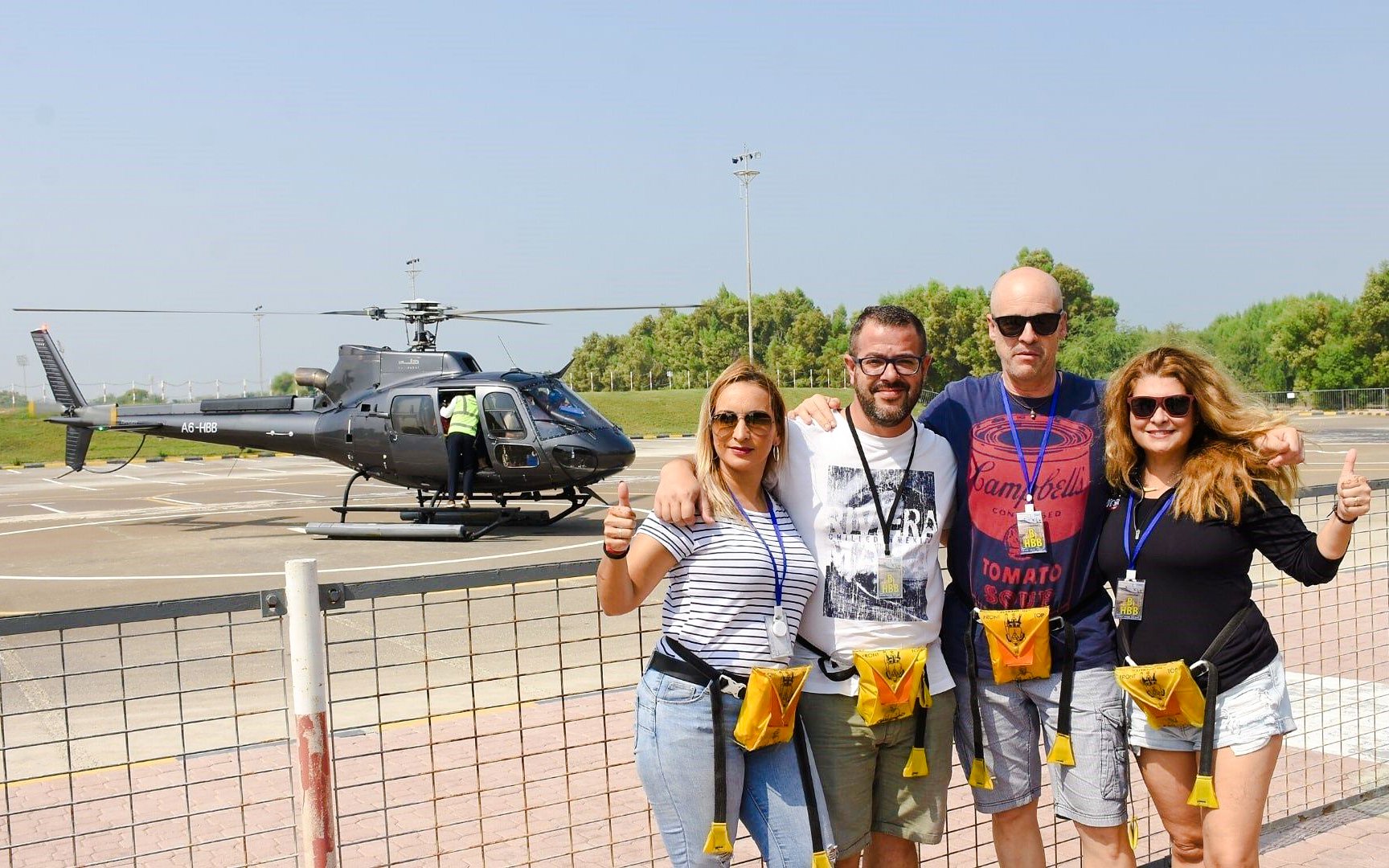 Visitors posing near helicopter after private tour at heli pad.
