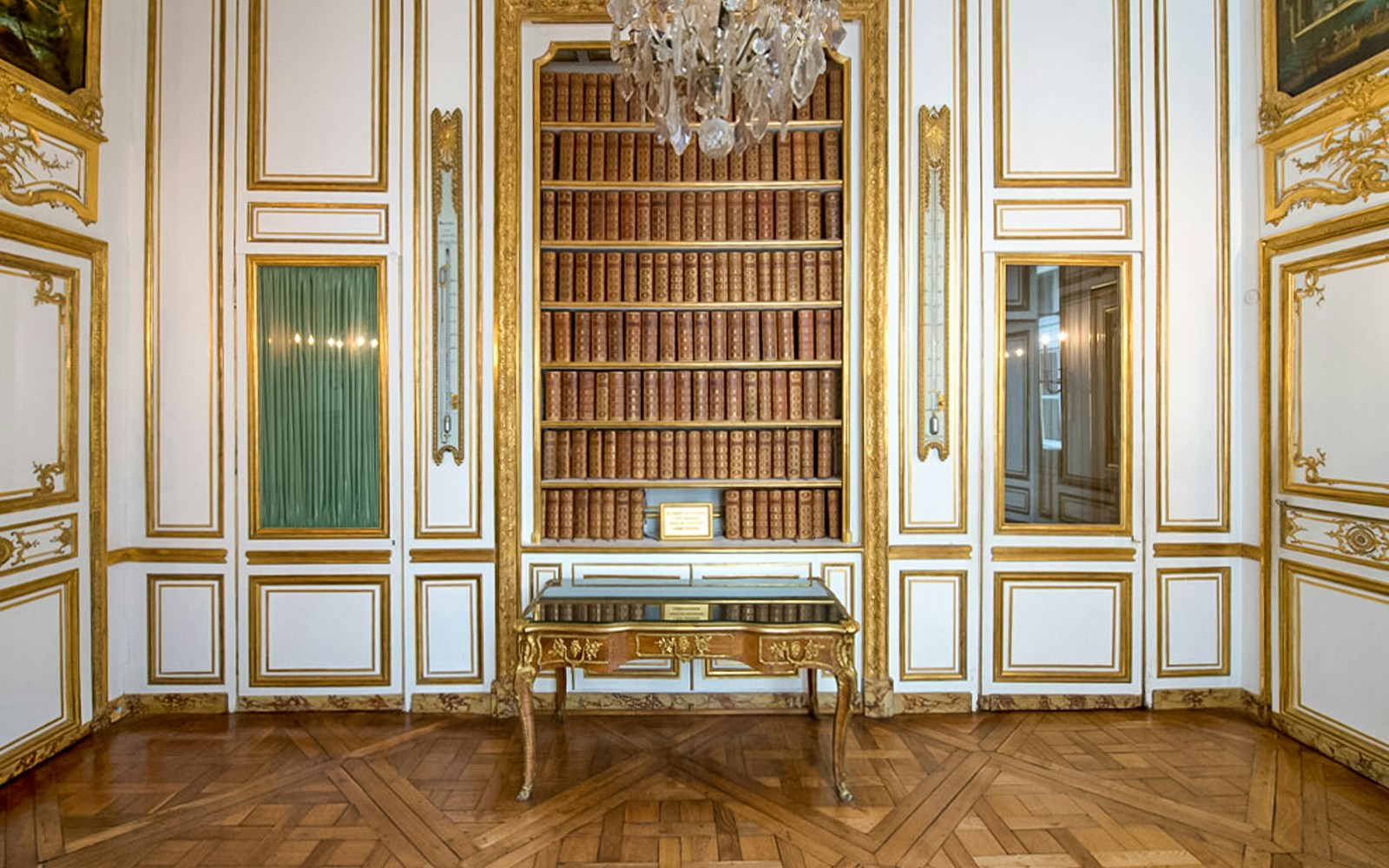 Ein reich verzierter Raum im Schloss Versailles mit goldenen Details, Gemälden und einem großen Kamin