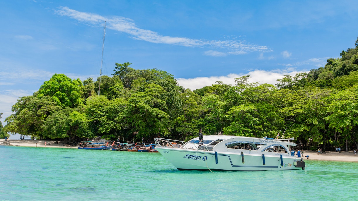 Speedboat near lush green island on Surin Islands tour, Thailand.